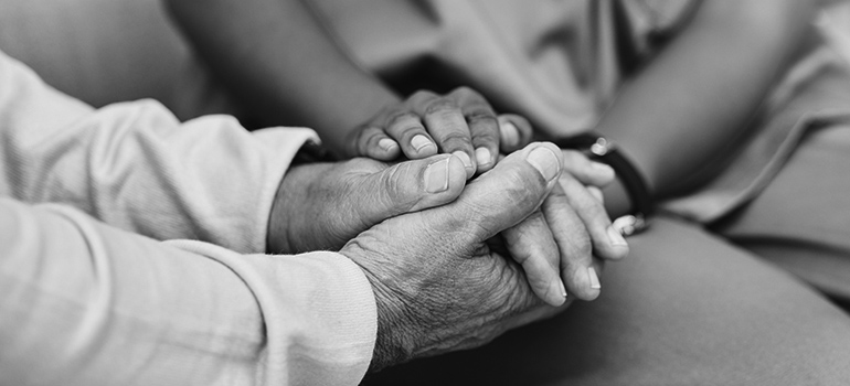 Vårdpersonal och patient håller varandras händer.